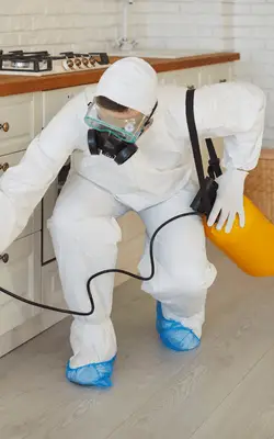 MelBuzz Pest Control technician in protective gear applying termite treatment in a Melbourne home, safeguarding