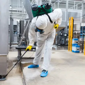 MelBuzz Pest Control technician in protective gear using a sprayer, demonstrating professional pest management services