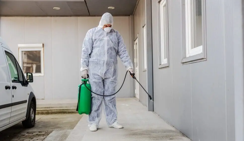 MelBuzz&trade; pest control technician in protective suit spraying for pest management and termite treatment in